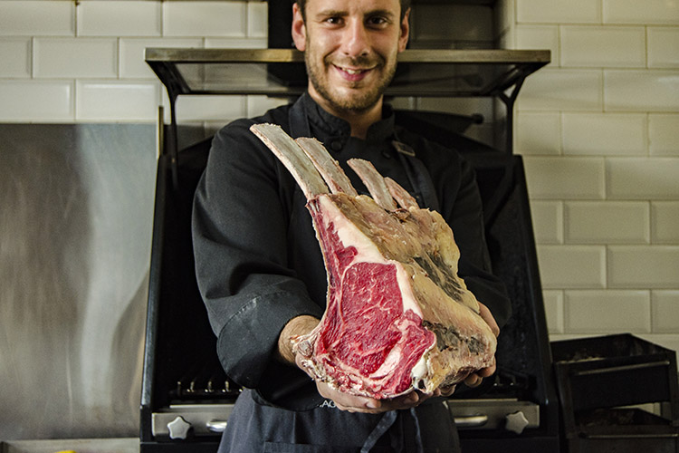 El chef Jorge Ramajo sostiene varios “tomahawk” de Retwagyu, nuestra carne única. Este corte recibe el nombre de “tomahawk” por su similitud a las hachas que llevaban las tribus indígenas norteamericanas. Habitat Ciguena Negra. Hotel rural - Asador - Hammam - Oleoturismo. Hotel situado en plena dehesa junto a Valverde del Fresno, Caceres, Extremadura. www.habitatcn.com Tel: 676 829 172  Foto: Alberto Paredes / @labombillaroja